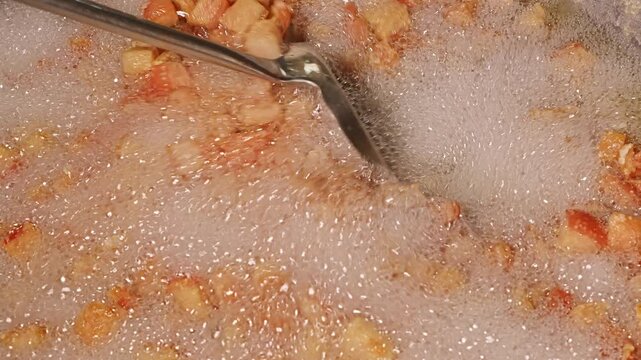 Fresh pork skin pieces frying in bubbling oil, capturing the essence of homemade crispy pork rind snack.