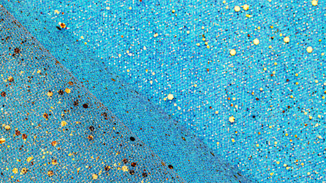 Colorful fabric with texture and pattern in blue tones scattered with shiny elements in a bright light setting