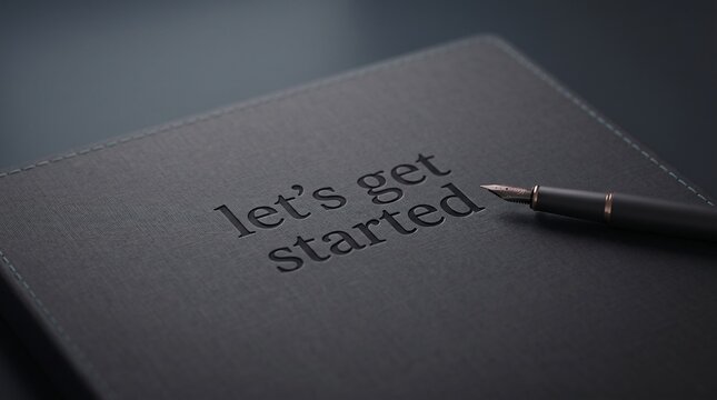Elegant black leather journal featuring embossed lets get started text beside a sophisticated fountain pen on dark background