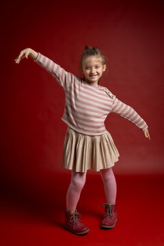 Smiling Little Girl Posing in Studio. Full Length Child Portrait with Playful Expression and Fashionable Clothing