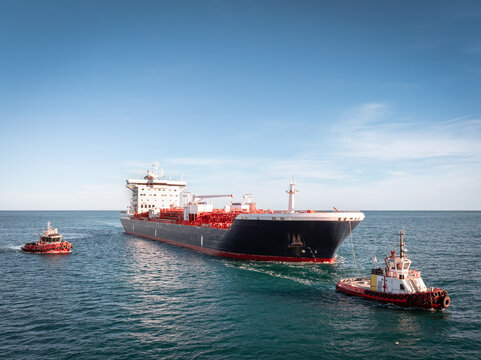 Large oil tanker ship escorted by two tugboats. Concept of maritime transport, global logistics, and international trade.