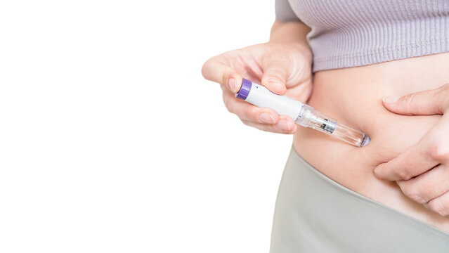 Woman injecting GLP-1 weight loss medication into stomach isolated on light background
