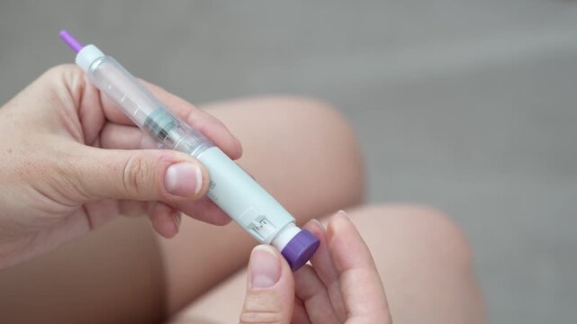 Woman setting dosage clicks on GLP-1 injection pen close-up