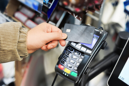hand holding credit card. A customer hand holds a black debit card near a point of sale terminal for a contactless payment transaction. High quality photo. Credit Card. Payment Terminal ready to purch