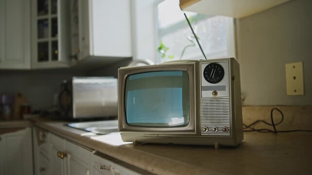An old black and white television displays grainy static in a charming kitchen filled with warm lighting. This vintage device evokes feelings of nostalgia and retro charm, perfect for Halloween