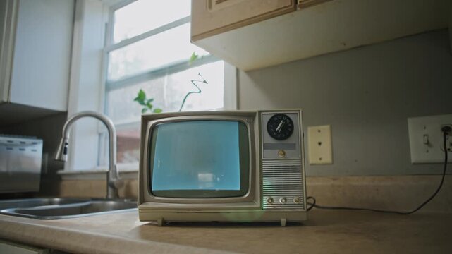 Old-fashioned television stands in a warm kitchen, displaying captivating black and white interference. A charming glimpse into retro technology and cozy decor, perfect for Halloween vibes