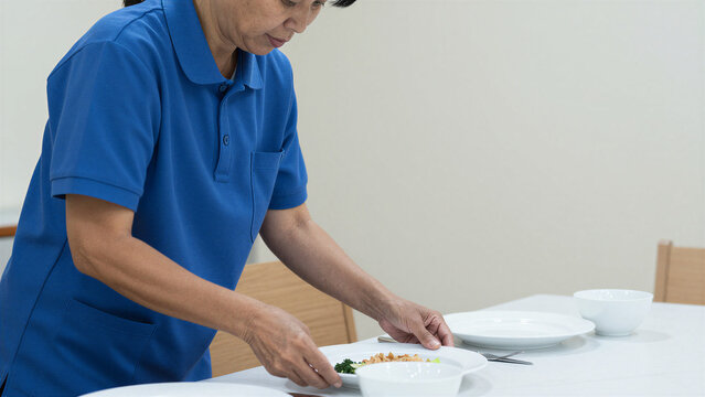 Foreign Female Caregiver Preparing Dishes for Senior Meal Service in Japan, Copy space on the right