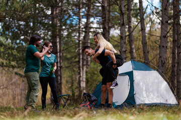 Fototapeta premium Friends enjoying a fun camping trip with laughter and companionship in a serene forest setting under clear blue skies