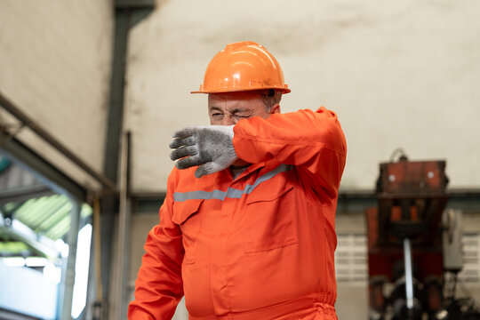 Construction worker wiping sweat from his face in a factory