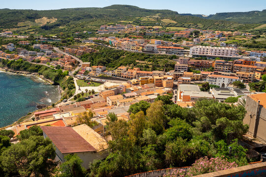 High angle view of coastal resort town Lu Bagnu with colorful houses and hotels on a green hillside, Sardinia, Italy