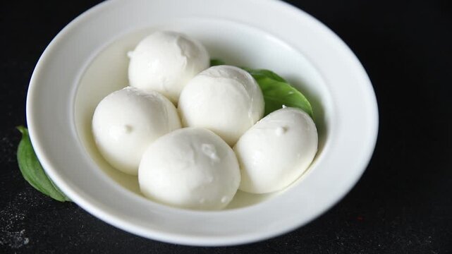 Mini mozzarella or mini burrata soft, young cheese lunch or dinner tasty snack organic fresh and gourmet food background on the table rustic food top view copy space