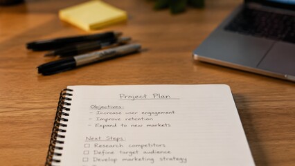 Obraz premium Notebook with project plan objectives on wooden desk.