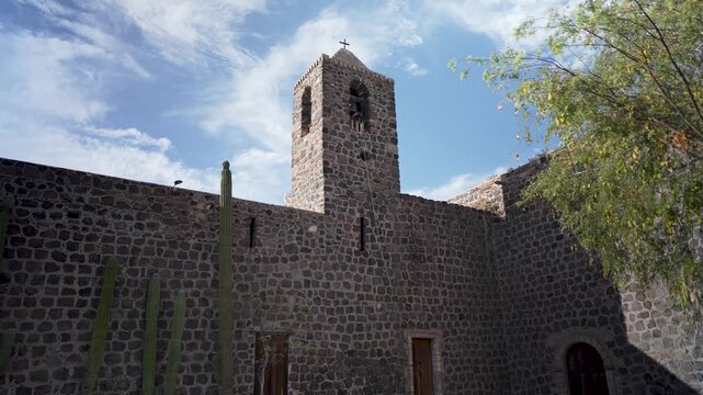 Visit Mission Church Santa Rosalia in Mulege, Baja California Sur, Mexico, and discover its history amid palm trees and desert mountains.