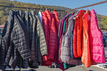 Winter Outdoor Clothing Insulated Puffer Down Jackets and Vests Hanging at Railing © markobe