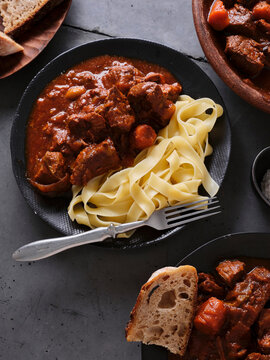 Slow cooked shredded beef served with pasta and bread in a home kitchen setting during dinner time