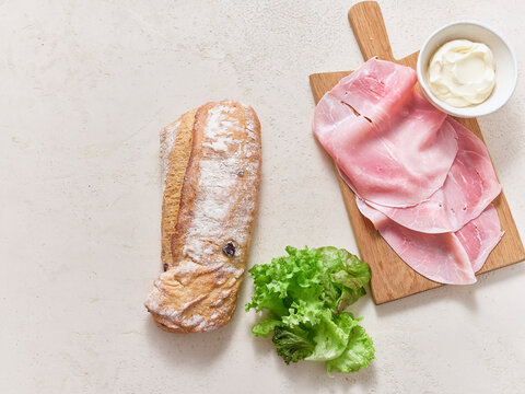 Making a sandwich with ciabatta olive bread, ham, lettuce, and mayonnaise for a healthy lunch preparation