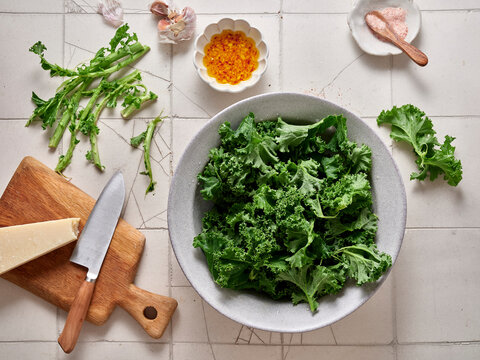 Preparing a simple kale salad with parmesan and garlic dressing on a kitchen counter in the afternoon