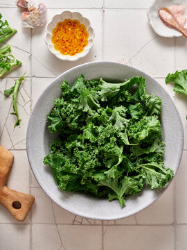 Making kale salad with parmesan and garlic dressing in a kitchen setting on a sunny day with fresh ingredients