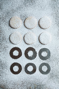 Top view of Linzer cookies with red jam and powdered sugar on a rustic surface