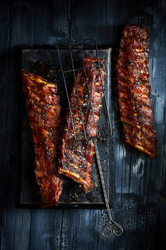 Sticky glazed BBQ pork ribs on a dark rustic wooden background.