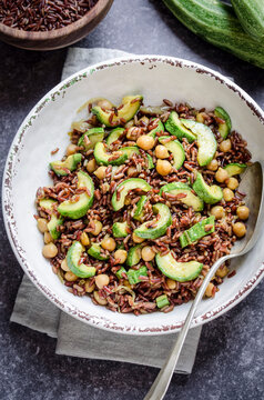 Red rice salad with chickpeas and zucchini in a bowl