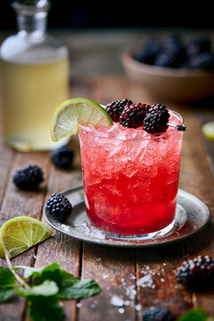 A vibrant Blackberry Smash cocktail sits in a rustic rocks glass filled with crushed ice, garnished with fresh blackberries