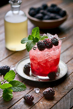 A vibrant Blackberry Smash cocktail sits in a rustic rocks glass filled with crushed ice, garnished with fresh blackberries
