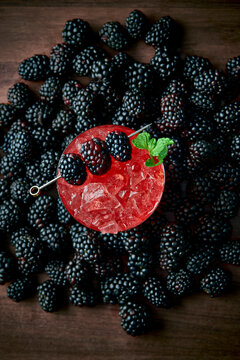 A vibrant Blackberry Smash cocktail sits in a rustic rocks glass filled with crushed ice, garnished with fresh blackberries