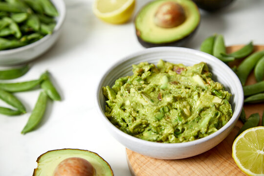 Guacamole and Vegetables on a Light Marble Background
