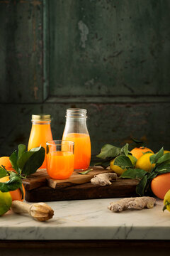 fresh organic lemon and orange juice squeezed and filled in glass jars and glasses and placed on a marble table top