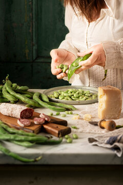 Fresh fave beans being shelled by a woman to make it ready to eat