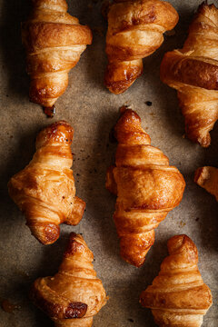 Tray of freshly baked golden croissants, arranged on baking paper.