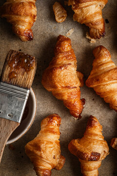 Tray of freshly baked golden croissants, arranged on baking paper.