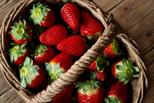 Basket of strawberries, on wooden table.