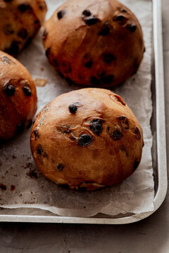 Freshly baked chocolate chip buns on parchment paper.