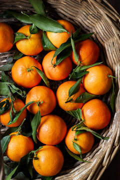 A rustic wicker basket filled with fresh clementines.