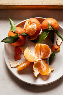 A dish with fresh clementines and some clementines sliced.