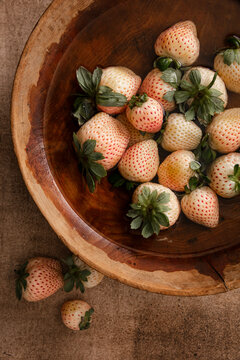Fresh pineberries soaking in a wooden bowl