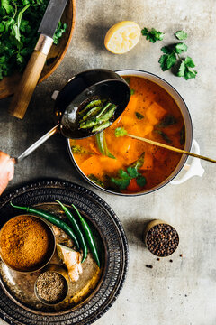 A pot of aromatic rasam simmering with tomatoes, spices, and herbs.