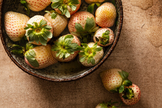 Fresh pineberries soaking in a dark bowl