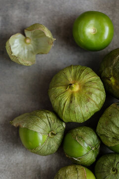 Fresh green tomatillos with husks on a marble surface