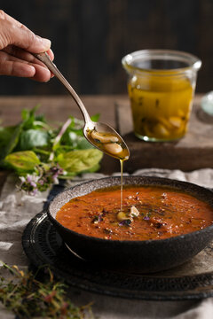Roasted tomato soup being drizzled with aromatic garlic olive oil