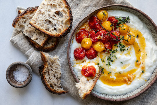 Roasted cherry tomatoes on vine served over creamy yogurt with herbs