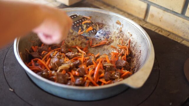 Fry meat, carrots, onions, in a large cast-iron cauldron, for cooking pilaf	