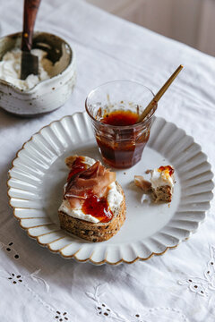 Sourdough toast topped with prosciutto, ricotta, and jam on plate
