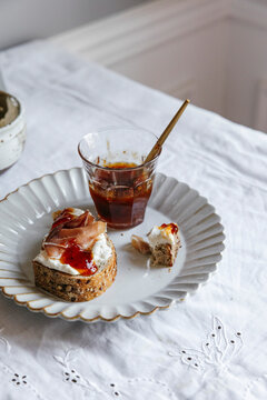 Sourdough toast topped with prosciutto, ricotta, and jam on plate