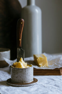 Rustic butter in ceramic jar with knife and block on table