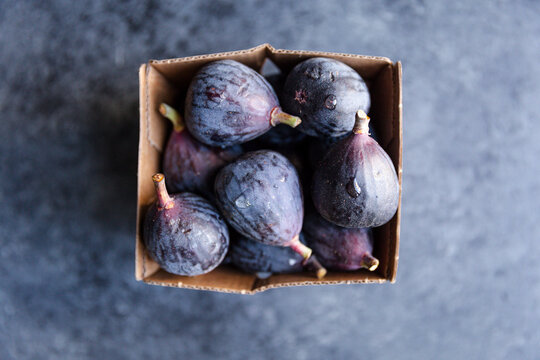 Fresh black figs in a small cardboard carton