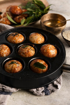 Kuzhi paniyaram in a cast-iron pan with spices