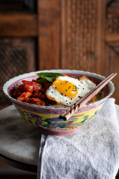 Spicy pork bulgogi served in a Peranakan bowl with a fried egg on top